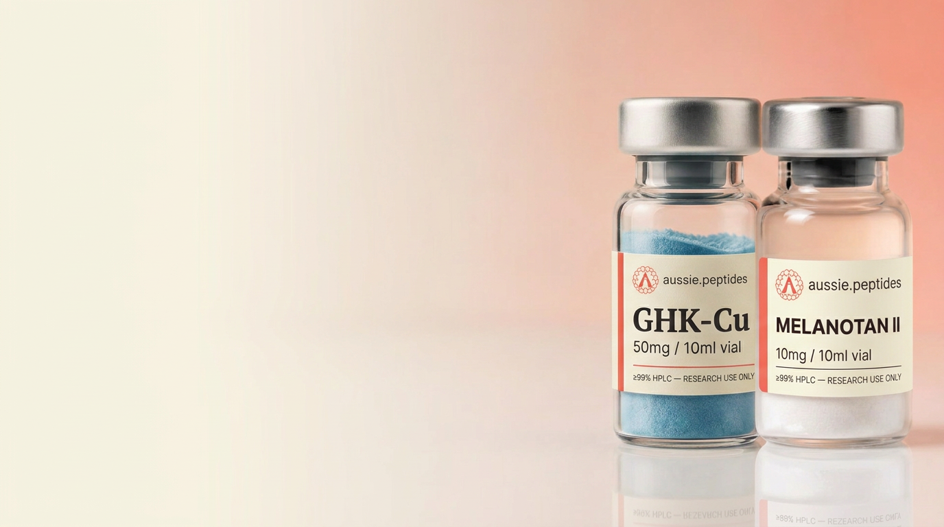 Aussie Peptides GHK-Cu and Melanotan II vials on a blush-pink studio backdrop — skin and hair research peptides, ≥99% HPLC verified, shipped in Australia